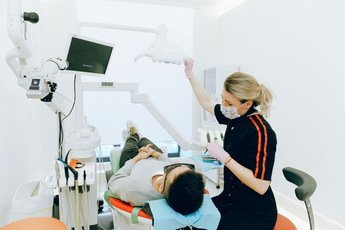 Profesional dental atendiendo a un paciente en una sala con equipamiento moderno